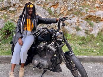 Black woman leaning against a motorcycle