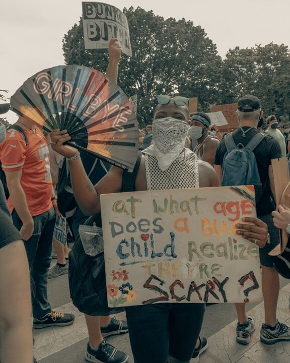 Black man holding fan and sign